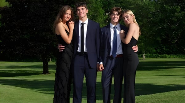 Cuatro estudiantes de la Fulford Academy están juntos en un campo con árboles al fondo.