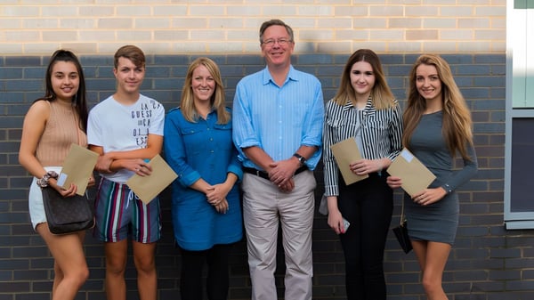 Un grupo de seis personas está frente a una pared de ladrillo en el terreno de la Fulston Manor School.