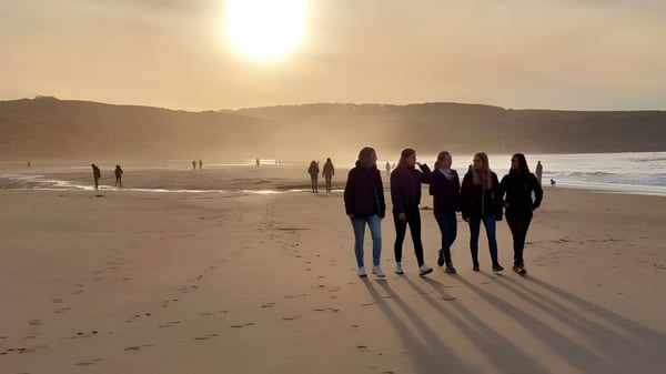 Un grupo de estudiantes de la Fyling Hall School camina por la playa al atardecer.
