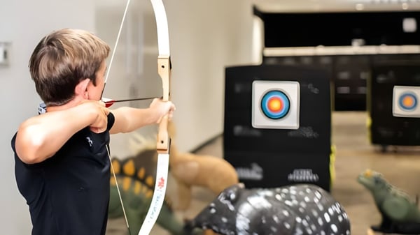Un estudiante de la Gallen Community School apunta con un arco a un blanco en el fondo.