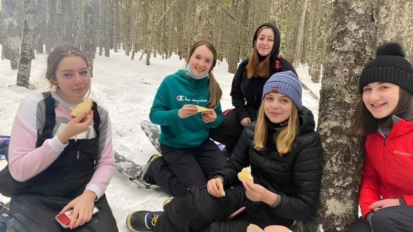 Un grupo de estudiantes de Gander Collegiate está vestido de invierno en un bosque nevado.