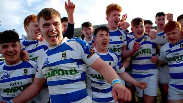 Un grupo de jóvenes jugadores de rugby en camisetas azules y blancas celebra en el campo del Garbally College.