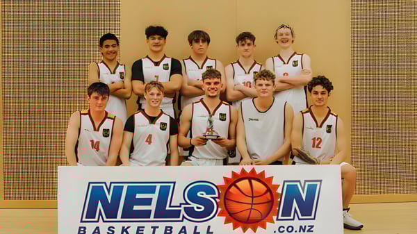 Un grupo de estudiantes del Garin College posan en el gimnasio con un trofeo de baloncesto.
