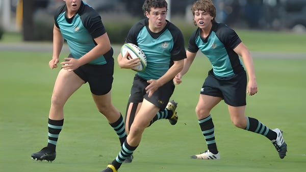 Tres jugadores de rugby de la Geelong Grammar School corren con el balón sobre un campo verde.