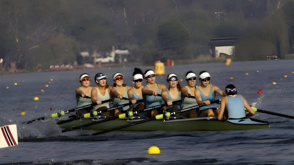 Un grupo de estudiantes de la Geelong Grammar School rema en un cuerpo de agua frente a un paisaje boscoso.