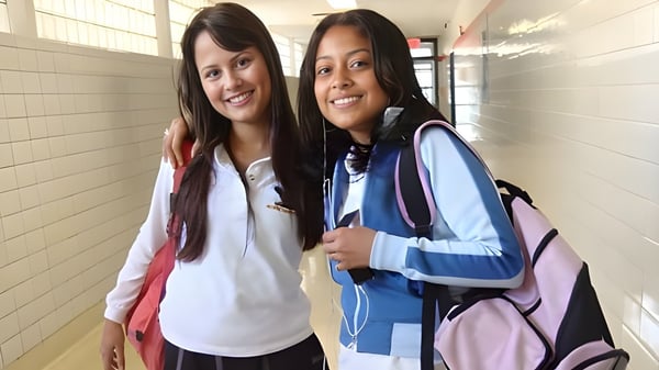 Dos estudiantes están sonriendo en el pasillo del George Harvey Collegiate Institute y conversan.