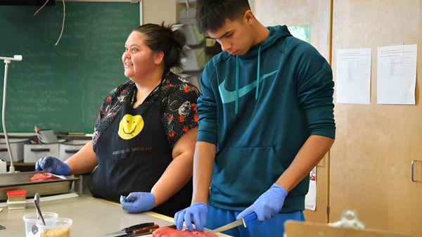 Dos estudiantes de la Georges P. Vanier Secondary School trabajan juntos en un laboratorio con guantes de protección.