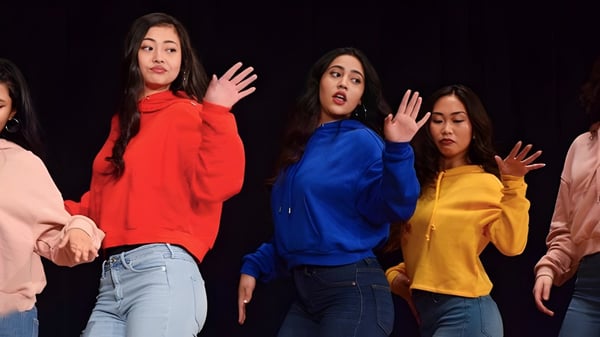 Un grupo de alumnas de la Georges Vanier Secondary School está en el escenario mostrando una expresión con las manos levantadas.