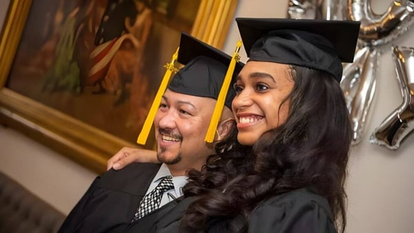 Un hombre mayor y una mujer más joven posan juntos en la ceremonia de graduación de Georgetown District High School.