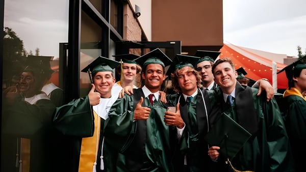 Un grupo de graduados en togas verdes está frente a un edificio celebrando su graduación en Gilbert Christian Schools.