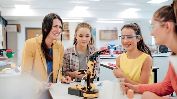 Un grupo de jóvenes estudiantes se está conversando y examinando un objeto en una mesa en Gilbert Public Schools.