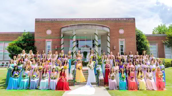 Un gran grupo de alumnas de la Girls Preparatory School se reúne frente a un gran edificio de ladrillo con una entrada curva.