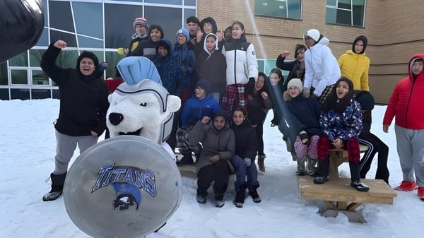 Un grupo de estudiantes y adultos está frente al edificio de la École secondaire publique Gisèle-Lalonde con una gran mascota inflable.