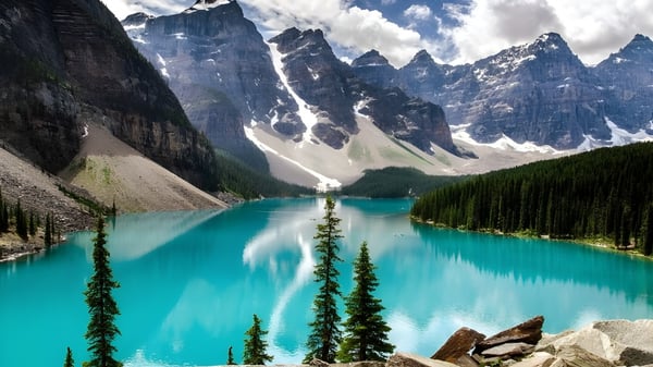 Un lago de montaña color turquesa frente a picos cubiertos de nieve rodeados de bosques perennes cerca del Glebe Collegiate Institute.