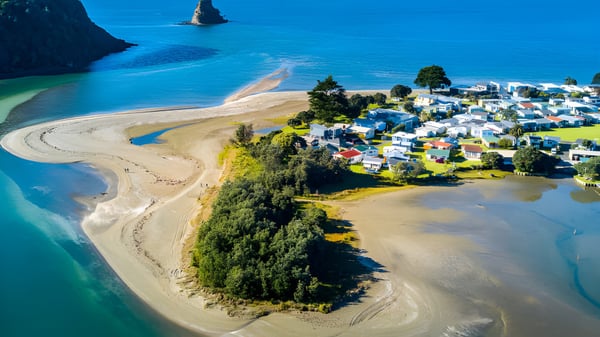 Una pintoresca ciudad costera con colinas verdes y agua turquesa cerca del Glenfield College.
