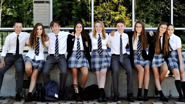Un grupo de estudiantes está junto en el campus de la Glenlyon Norfolk School frente a edificios y áreas verdes.