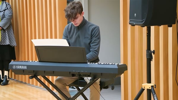 Una persona toca el teclado en el aula de música de la Glenstal Abbey School con paredes revestidas de madera.