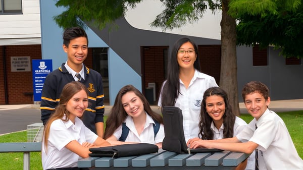 Un grupo de estudiantes se encuentra frente al edificio escolar de la Glenunga International High School rodeado de árboles y áreas verdes.