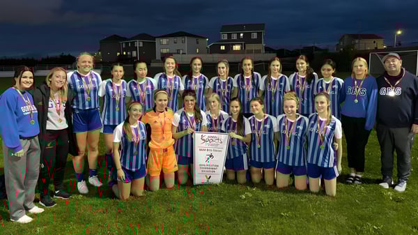 Un grupo de jugadoras de fútbol de la Gonzaga High School están juntas en un campo de juego por la noche.