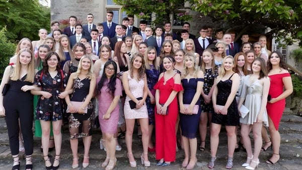 Un grupo de estudiantes vestidos formalmente posan frente a un edificio de piedra en el campus de la Gordonstoun School.