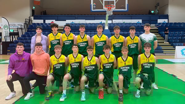 Un grupo de estudiantes de la Gortnor Abbey posan juntos en la cancha de baloncesto con el aro de fondo.
