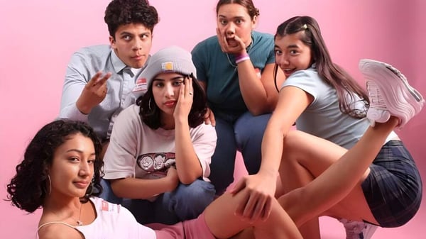 Un grupo de estudiantes de la Grand Arts - Ramon C. Cortines School of Visual and Performing Arts posan juntos frente a un fondo rosa.