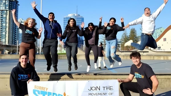 Estudiantes de la Grandview Heights Secondary School saltan y celebran frente a un moderno paisaje urbano.