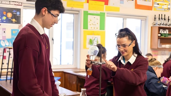 Dos alumnos conversan en el aula de la Grange Post Primary School frente a materiales de enseñanza.