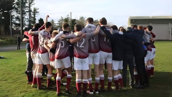 Un grupo de alumnos se encuentra en una reunión en el campo del terreno de la Grange Post Primary School.