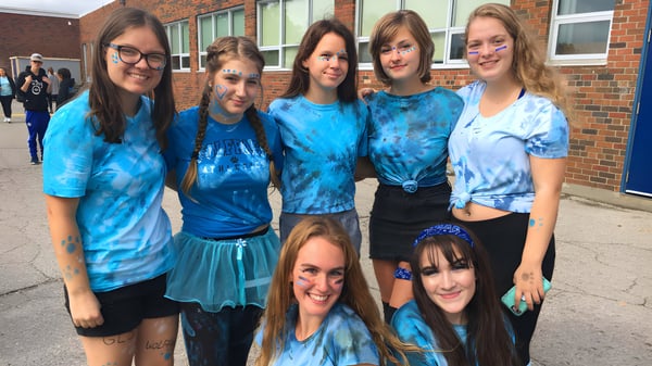 Un grupo de estudiantes de la Great Lakes District Secondary School está frente a un edificio de ladrillo.