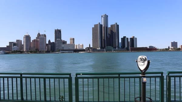 Un telescopio está en primer plano con vista a la línea del horizonte de una gran ciudad junto al agua en el terreno del Greater Essex County District School Board.