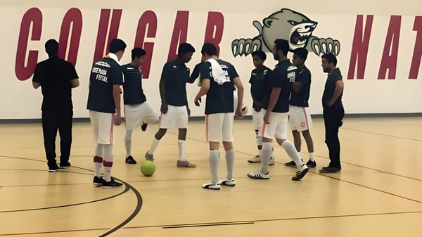 Un grupo de estudiantes de la Green Fields High School está juntos en la cancha de baloncesto frente a un gran mural.