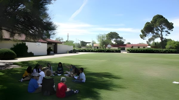 Un grupo de estudiantes está en el campo cubierto de hierba en el terreno de la Green Fields High School.