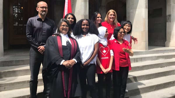 Un grupo de estudiantes de la Greenwood Secondary School posan en las escaleras frente a un edificio después de la ceremonia de graduación.