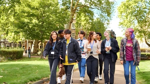 Un grupo de estudiantes camina juntos por un camino en el campus verde de la Guildhouse School London.