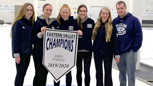 Estudiantes de la G.W. Graham Secondary School sostienen un banner como campeonas del Eastern Valley en Girls Curling 2019/2020.