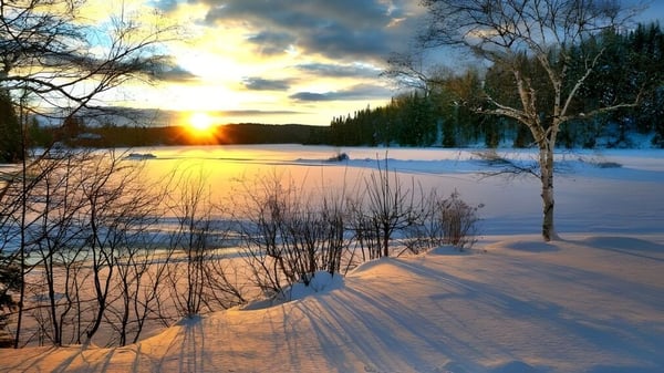 Un paisaje invernal nevado con un lago congelado y un atardecer cerca de la Haliburton Highlands School.