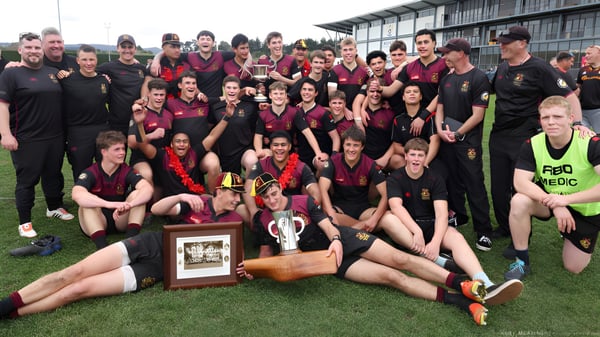 Un grupo de estudiantes de la Hamilton Boy's High School posan en el césped con un trofeo en primer plano.