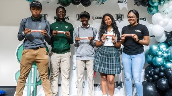 Estudiantes de la Hamilton Christian Academy están frente a una pared con imágenes deportivas.