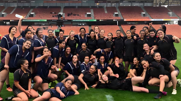 Un gran grupo de alumnas de la Hamilton Girl's High School posan en el campo deportivo frente al estadio.