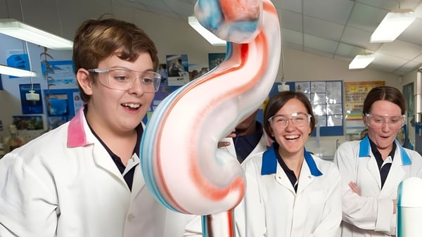 Tres personas con batas de laboratorio con un gran modelo de corazón colorido en clase en el Hamilton Secondary College.