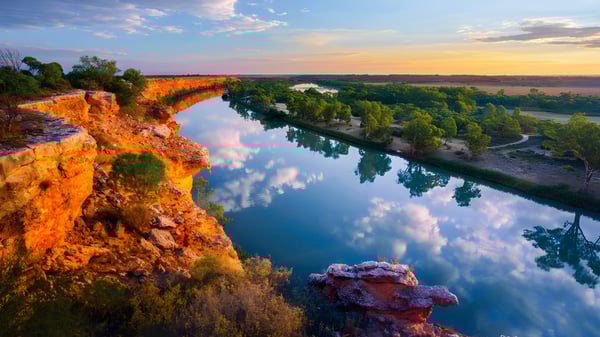 Un tranquilo paisaje fluvial en un valle boscoso al atardecer.
