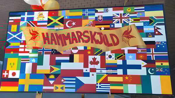 Un gran banner con la inscripción Hammarskjold High School rodeado de un collage de varias banderas nacionales.