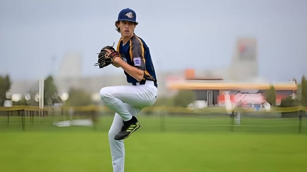 Un jugador de béisbol está en el campo de Hampton Senior High School frente a un paisaje urbano.