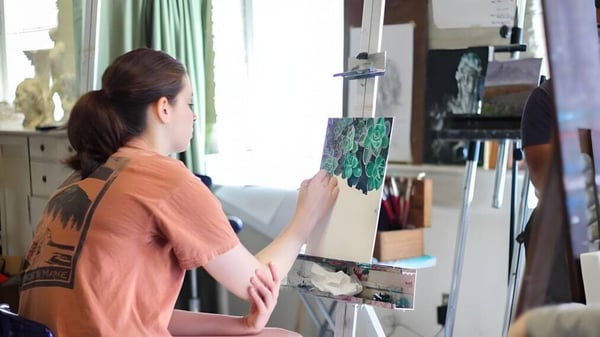 Una estudiante de la Hanham Woods Academy está en una habitación pintando en un caballete.