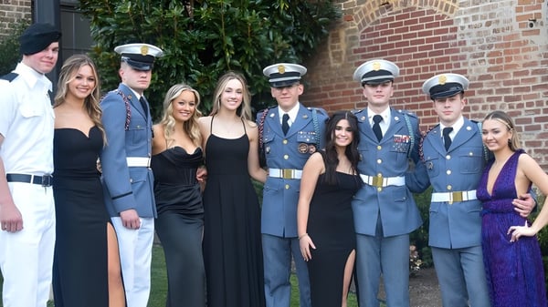 Estudiantes y personal militar de la Hargrave Military Academy posan frente a un edificio de ladrillo con hiedra en la pared.