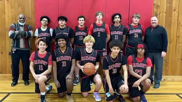 Un grupo de estudiantes de la Harmony Christian School posan juntos en el gimnasio durante el baloncesto.