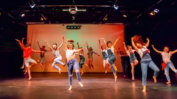Estudiantes del Havant College realizan un dinámico espectáculo de danza en un escenario con luces de colores.