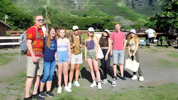 Un grupo de estudiantes está reunido en un área verde al aire libre en el campus de la Hawai'i Pacific University.