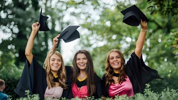 Tres estudiantes celebran su graduación en el campus del Hazelwood College en el área exterior verde.